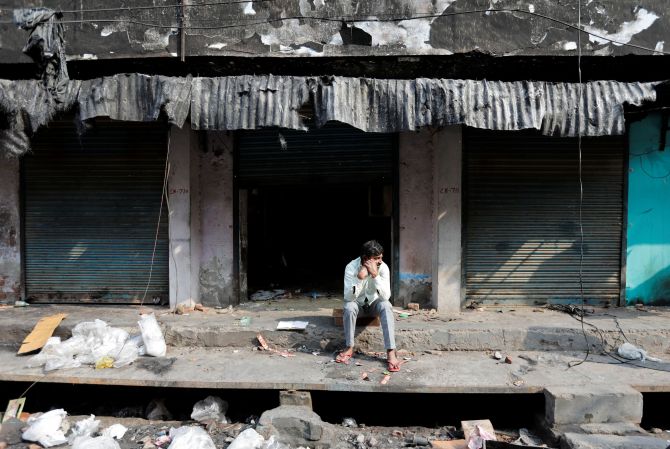 A man sits in front of burnt out properties owned by Muslims in a riot affected area following clashes between people demonstrating for and against a new citizenship law in New Delhi, India, March 2, 2020. REUTERS/Danish Siddiqui -
