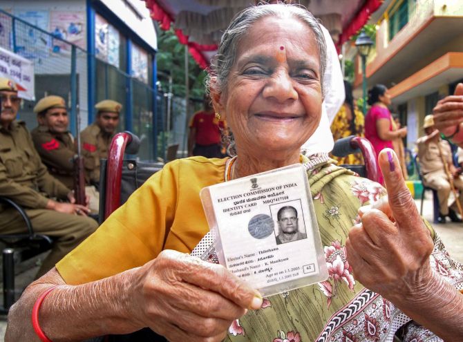 A elderly woman holds her voter identity card as she shows her inked finger after casting vote during the bye-poll of Mahalaxmi Layout constituency, in Bengaluru, Thursday, Dec. 5, 2019. (PTI Photo)
