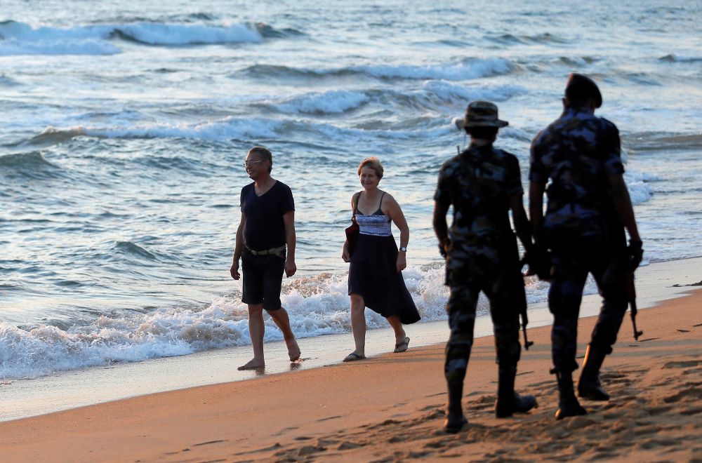 Tourists walk on a beach as Sri Lanka's military patrol the area as part of security measures after April 21 Easter Sunday bomb attacks on hotels and churches, in Colombo, Sri Lanka July 30, 2019. REUTERS/Dinuka Liyanawatte/File photo