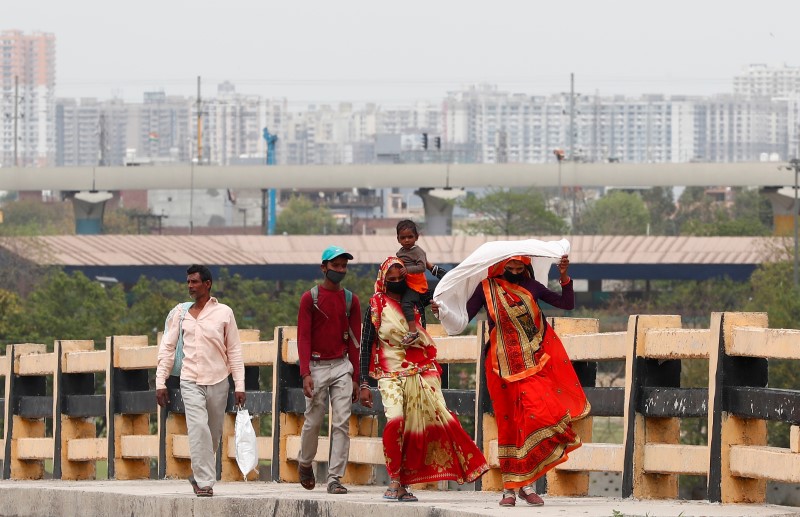 A migrant worker carries her daughter as she walks on a highway with others looking out for a transport to return to their villages, after India ordered a 21-day nationwide lockdown to limit the spreading of coronavirus disease (COVID-19), in Ghaziabad, o