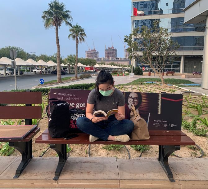 A girl wearing a face mask reads a book, following the outbreak of coronavirus disease (COVID-19), in Dubai, United Arab Emirates March 26, 2020. REUTERS/Ahmed Jadallah - RC2SRF980C57