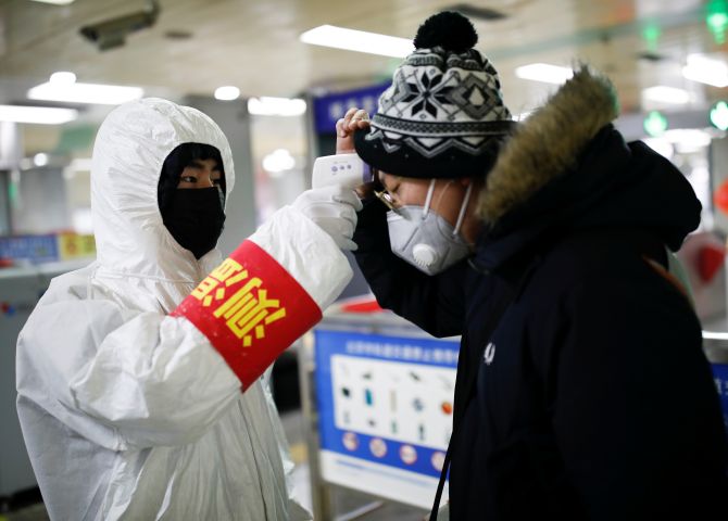 A staff member checks the temperature of a passenger entering a subway station, as the country is hit by an outbreak of the new coronavirus, in Beijing, China. Photograph: Carlos Garcia Rawlins/Reuters