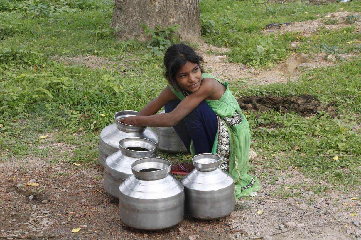 A girl cleans her metal water pots in Bundelkhand, India on July 16, 2019. Thomson Reuters Foundation/Annie Banerji