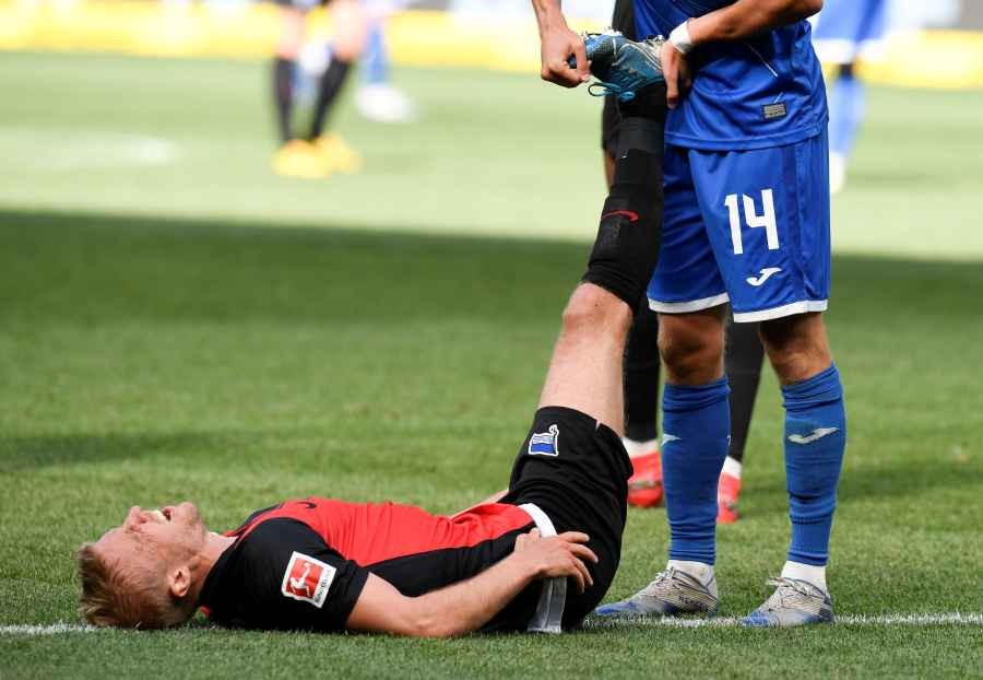 Hertha's Per Ciljan Skjelbred is helped by Hoffenheim's Christoph Baumgartner, as play resumes behind closed doors following the outbreak of the coronavirus disease (COVID-19) (Reuters File Photo)