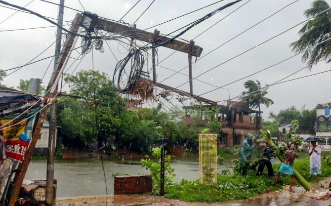 Workers try to restore a power line after a tree fell on it during a storm due Cyclone Amphan, in Burdwan district of West Bengal. Photograph: PTI Photo