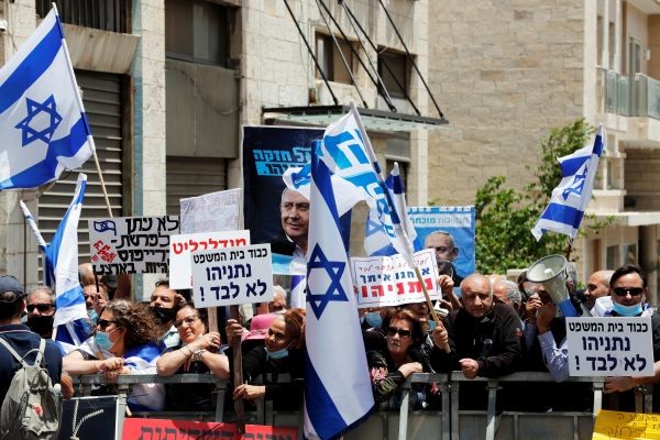 Supporters of Israeli Prime Minister Benjamin Netanyahu wave Israeli flags and hold placards as they rally just before Netanyahu's corruption trial opens, outside the District Court in Jerusalem on May 24. (REUTERS Photo)