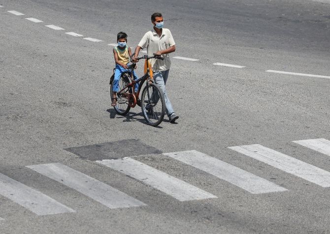 A man with his child on a bicycle is seen on a deserted road in Jammu during a nationwide lockdown. Photograph: PTI Photo