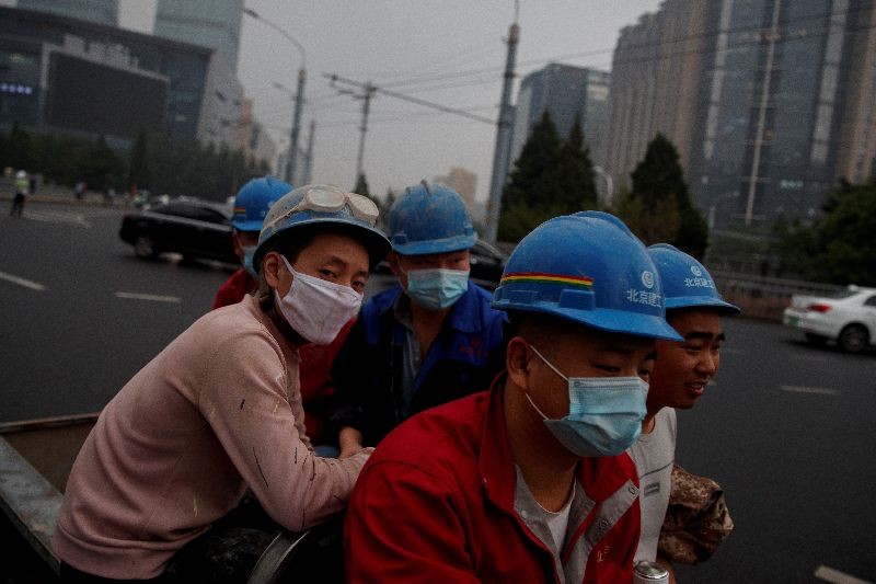 Workers wear protective masks as they sit on the back of an electric vehicle after working hours following the coronavirus disease (COVID-19) outbreak in Beijing, China May 21, 2020.  REUTERS/Thomas Peter/File photo