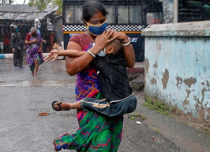 A woman carries her son as she tries to protect him from heavy rain while they rush to a safer place, following their evacuation from a slum area before Cyclone Amphan makes its landfall, in Kolkata. Photograph: Rupak De Chowdhuri/Reuters