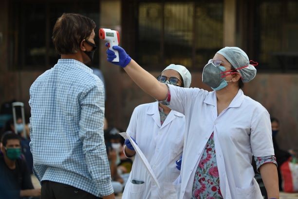 A health worker (R) checks the body temperature of a passenger before the departure of a special train service from Ahmedabad to New Delhi, at Sabarmati Railway Staion near Ahmedabad.