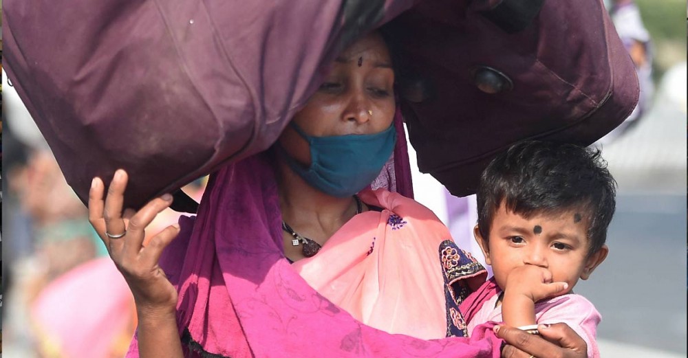 A migrant carrying a child arrives to board a train at Central Railway station in Chennai. Photo: PTI