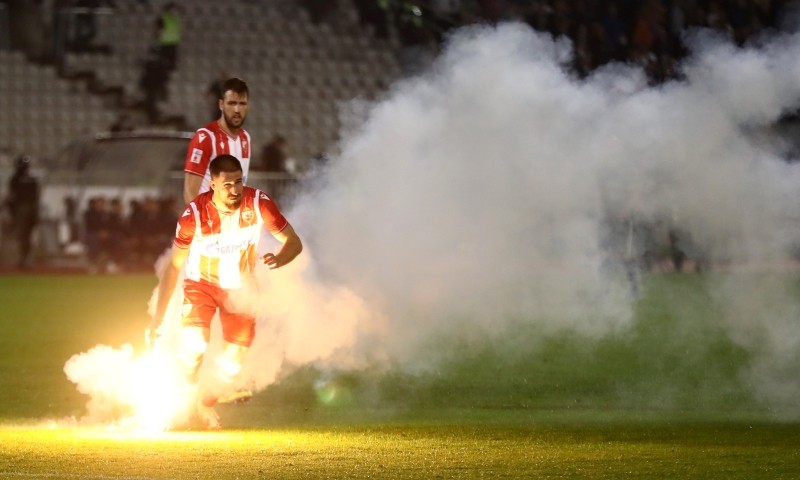 Crvena Zvezda's Milos Degenek takes a flare and carries it off the field, after Serbian authorities allowed play with fans following the outbreak of COVID-19. (Reuters Photo)