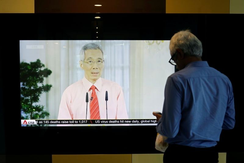 A man stands in front of a screen showing a telecast of Singapore's Prime Minister Lee Hsien Loong addressing the outbreak of coronavirus disease (COVID-19), at the central business district in Singapore on April 3, 2020. (REUTERS File Photo)