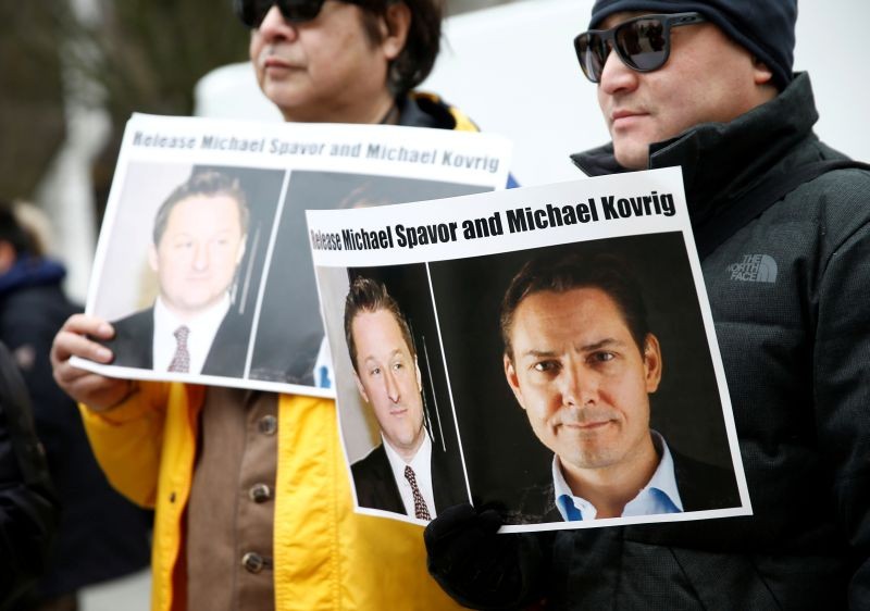 People hold signs calling for China to release Canadian detainees Michael Spavor and Michael Kovrig during an extradition hearing for Huawei Technologies Chief Financial Officer Meng Wanzhou at the B.C. Supreme Court in Vancouver, British Columbia, Canada on March 6, 2019.  (REUTERS File Photo)