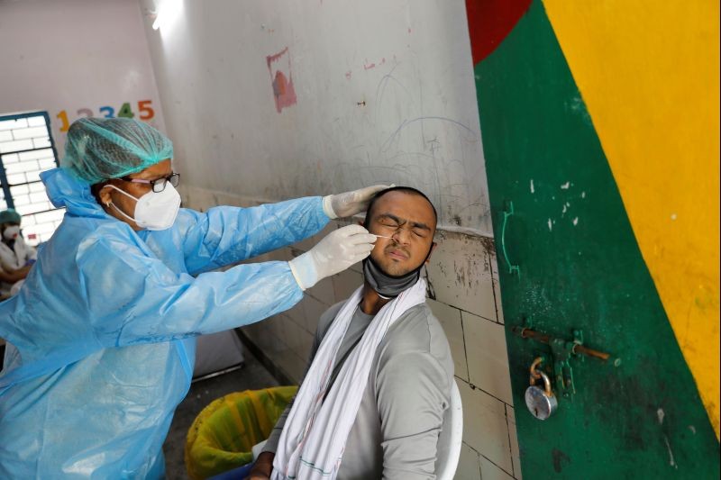 A medical health worker in a Personal Protective Equipment (PPE) collects sample using a swab from a man at a school that was turned into a centre for conducting tests for the coronavirus disease (COVID-19) amidst the spread of the disease, in New Delhi on June 23, 2020. (REUTERS Photo)