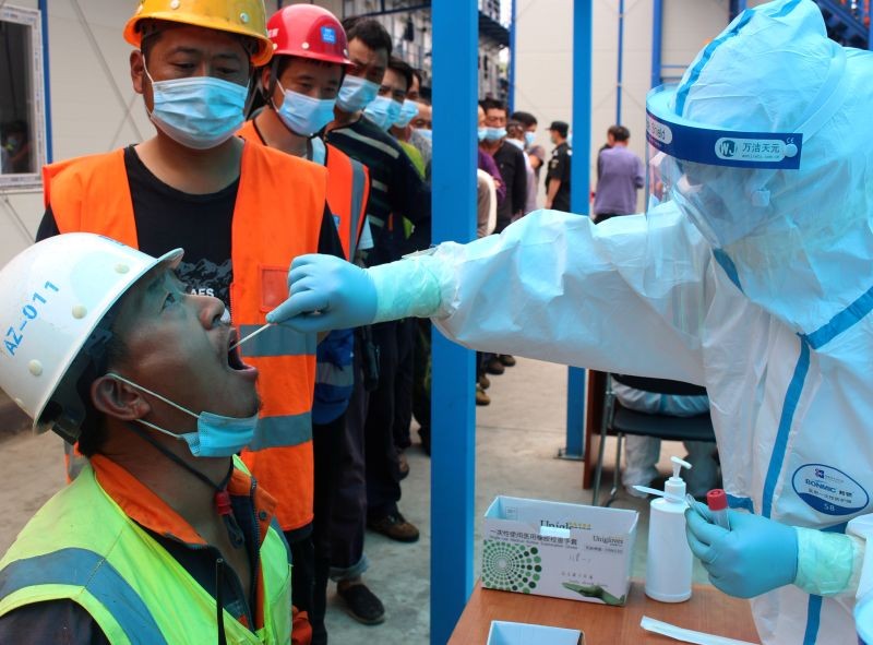 A medical worker in protective suit collects swabs from construction workers for nucleic acid tests following a new outbreak of the coronavirus disease (COVID-19) in Beijing, China on June 25, 2020. (REUTERS Photo)