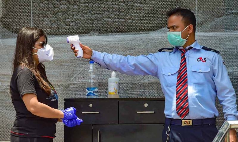 A security guard checks the temperature of a customer before allowing her to enter a liquor shop, amid COVID-19 lockdown in Bengaluru. (PTI Photo)