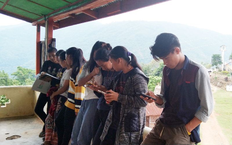 Students of class 10 are seen appearing their online evaluation test, huddled at the Village Council Hall of Chisholimi village, while the juniors discuss, post exams on Sunday, June 7. (Morung Photo)