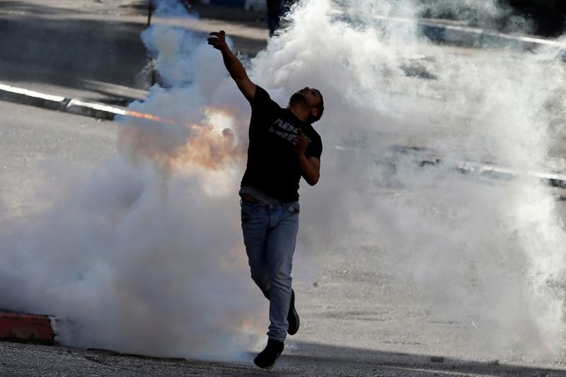 A Palestinian returns a tear gas canister fired by Israeli troops during a protest against Israel's plan to annex parts of the occupied West Bank, in Hebron on June 12, 2020. (REUTERS File Photo)