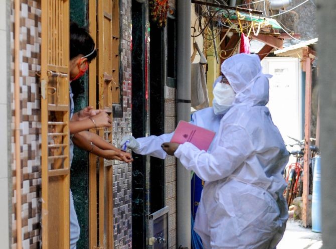 A health worker marks the hands of residents with home quarantine stamp, at Bhaji Galli Road no. 3 of Andheri East in Mumbai, on Saturday. Photograph: PTI Photo