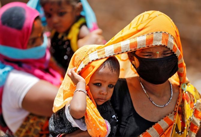 Migrant workers cover their children with saris, a traditional clothing worn by women, to protect them from heat as they wait to get on a bus to reach a railway station to board a train to their home state of eastern Bihar, during an extended lockdown to slow the spreading of the coronavirus disease (COVID-19), in Ahmedabad, India, May 20, 2020. REUTERS