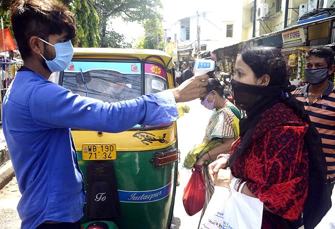 An auto driver checks the temperature of passengers before taking them on board in Kolkata. Photograph: ANI Photo