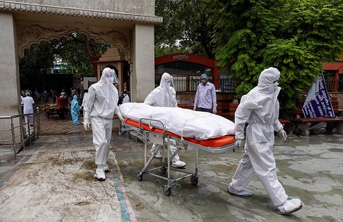 Health workers wearing Personal Protective Equipment carry the body of a person who died due to the coronavirus disease, at a crematorium in New Delhi. Photograph: Anushree Fadnavis/Reuters