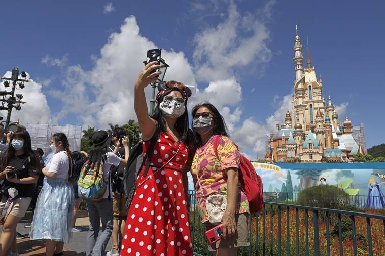 Visitors wearing face masks to prevent the spread of the new coronavirus, take a selfie at the Hong Kong Disneyland on Thursday, June 18, 2020.  (AP Photo)