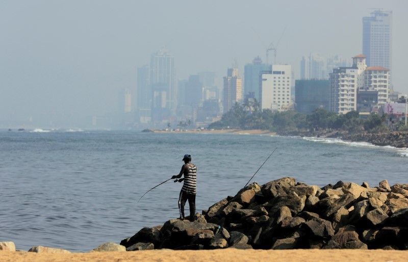 A man fishes near a deserted beach as the Colombo financial city is seen behind him during the curfew imposed by the government amid concerns of spread of the coronavirus disease (COVID-19), in Colombo, Sri Lanka on April 2, 2020. (REUTERS File Photo)