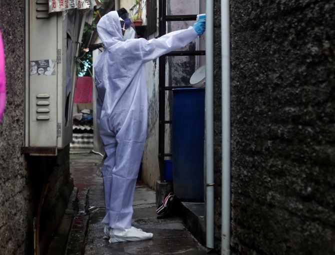 A healthcare worker wearing personal protective equipment checks the temperature of a resident of a slum area during a check-up camp for the coronavirus disease in Mumbai. Photograph: Francis Mascarenhas/Reuters