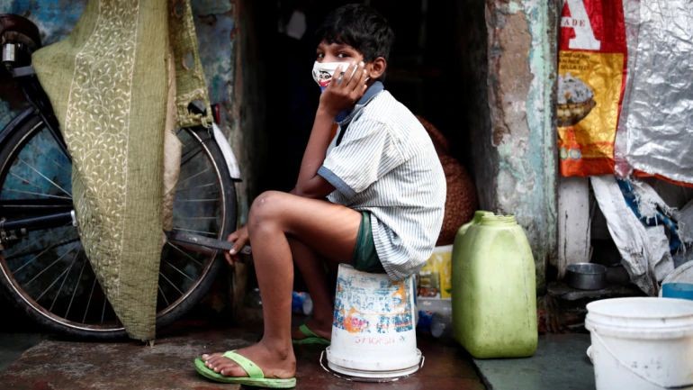 A boy wearing a protective face mask sits outside a house in New Delhi. (Photo:Reuters)