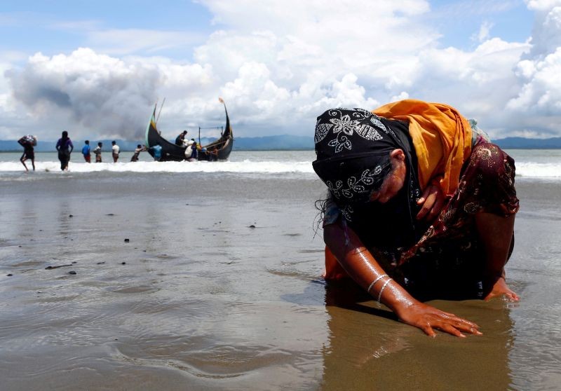 An exhausted Rohingya refugee woman touches the shore after crossing the Bangladesh-Myanmar border by boat through the Bay of Bengal in Shah Porir Dwip, Bangladesh on September 11, 2017. (REUTERS File Photo)