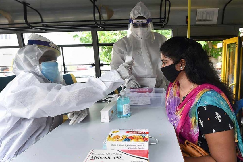 A health worker wearing PPE checks temperature of a girl at a mobile dispensary in Chennai. PTI Photo