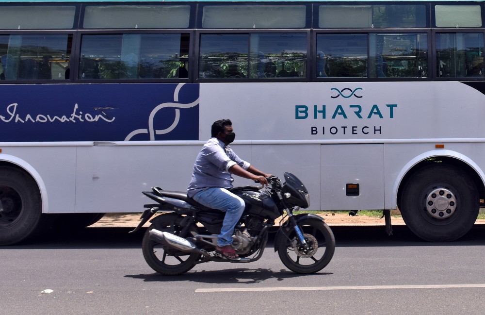 A man rides his motorbike past a parked bus of India's biotechnology company Bharat Biotech outside its office in Hyderabad on July 3. (REUTERS/Stringer File Photo)