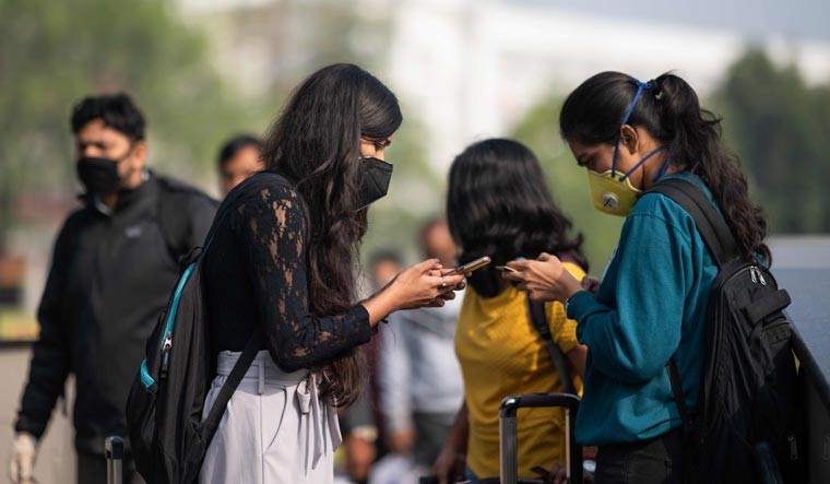 FILE PHOTO: Women wearing facemasks as a preventive measure against the COVID-19 coronavirus use their mobile phones outside a metro station in New Delhi | AFP Photo