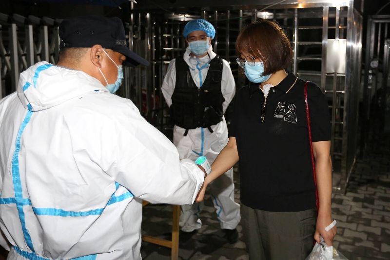 A worker in protective suit measures the body temperature of a woman at the entrance to a residential compound, following the coronavirus disease (COVID-19) outbreak in Urumqi, Xinjiang Uighur Autonomous Region, China early July 28, 2020. Picture taken July 28, 2020. cnsphoto via REUTERS