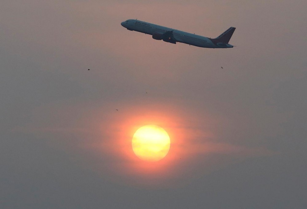 An Air India passenger plane passes the sun on a smoggy morning in Ahmedabad, India, December 4, 2019. REUTERS/Amit Dave/Files