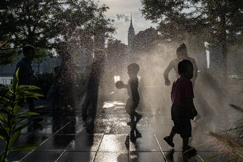 Children cool off in a fountain while enjoying a warm and humid day at Gantry Plaza State Park following the outbreak of the coronavirus disease (COVID-19), in Long Island City, New York, U.S., July 25, 2020. REUTERS/Jeenah Moon