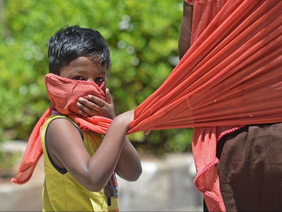 In this picture taken on July 8, 2020, a boy covers his face with the scarf of his mother as he walks along the road after the government eased a nationwide lockdown imposed as a preventive measure against the COVID-19 coronavirus, in Chennai, India.ARUN SANKAR / AFP via Getty Images