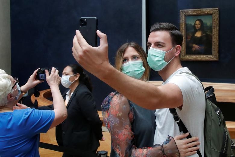 Visitors, wearing protective face masks, make a selfie in front of the "Mona Lisa" (La Joconde) by Leonardo Da Vinci at the Louvre museum in Paris, France, July 6, 2020. REUTERS/Charles Platiau