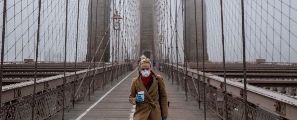 Woman in mask walks the Brooklyn Bridge during the COVID-19 pandemic. (Victor J. Blue/Stringer/Getty Images)
