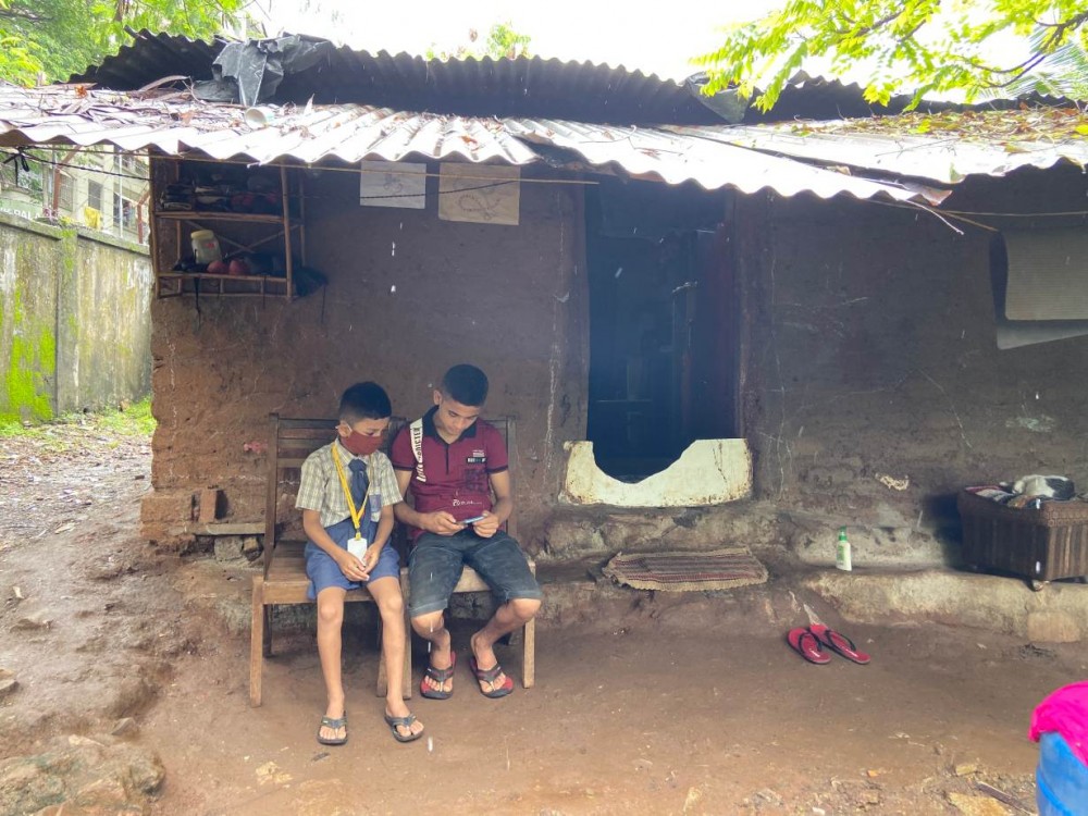 Gautam Suresh watches as his brother looks at their new smartphone outside their home in suburban Mumbai, India, on July 27, 2020. Thomson Reuters Foundation/Roli Srivastava
