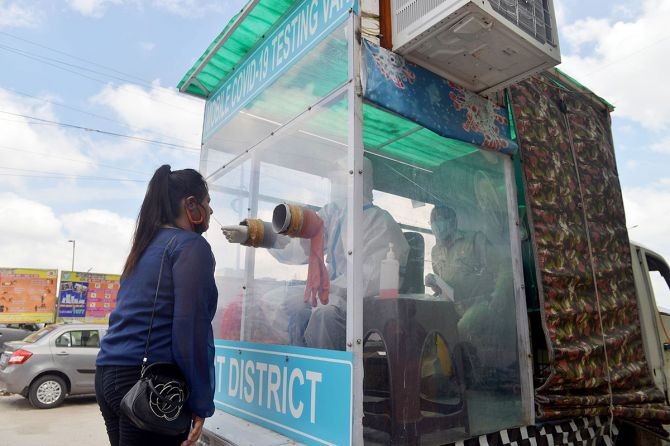 A health worker collects swab sample from a woman for COVID-19 infection at Mobile Testing van at East zone, in Delhi. Photograph: ANI Photo