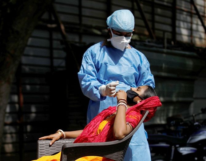 A healthcare worker takes a swab from a migrant laborer for a rapid antigen test at the site of an under construction residential complex in New Delhi. Photograph: Adnan Abidi/Reuters
