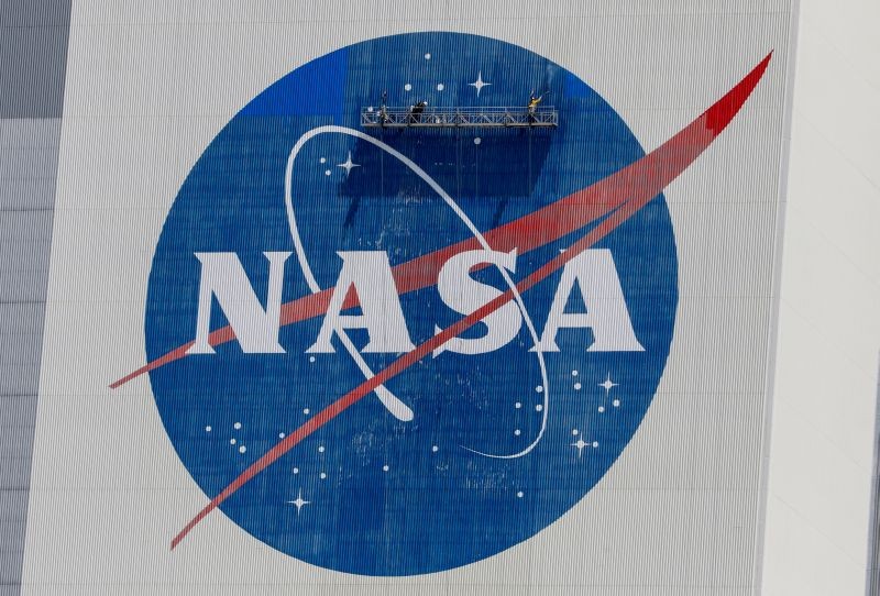 Workers pressure wash the logo of NASA on the Vehicle Assembly Building at the Kennedy Space Center in Cape Canaveral, Florida, U.S., May 19, 2020. REUTERS/Joe Skipper/File Photo