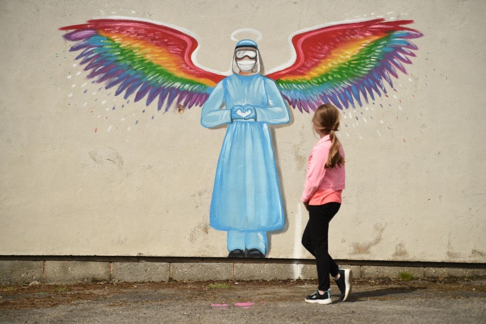 A girl looks at a mural by artist Rachel List paying tribute to NHS staff battling the COVID-19 outbreak painting on a wall in Pontefract, northern England. (Photo by Oli SCARFF / AFP)
