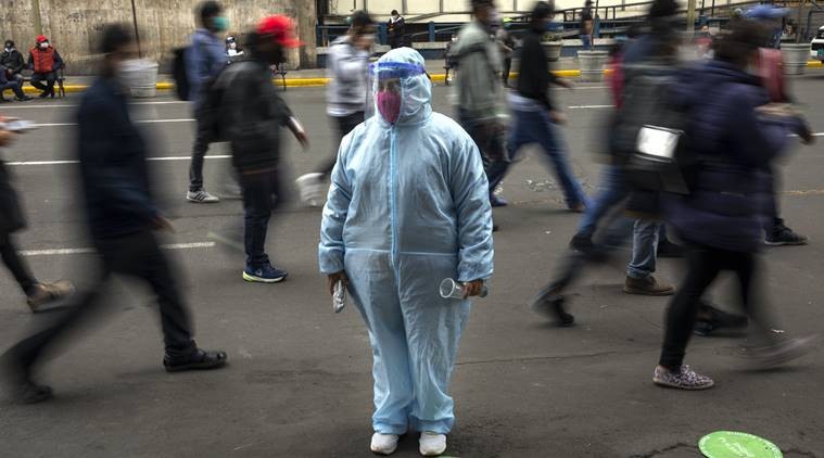 A woman waits outside a shop wearing protective gear due to the COVID-19 pandemic in downtown Lima, Peru. (AP Photo)