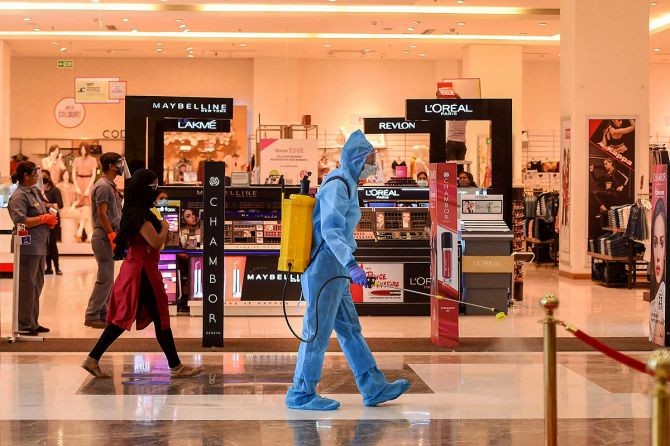 A worker wearing PPE kit sprays disinfectant inside a shopping mall after authorities eased restrictions during Unlock 4.0 in Chennai. Photograph: PTI Photo