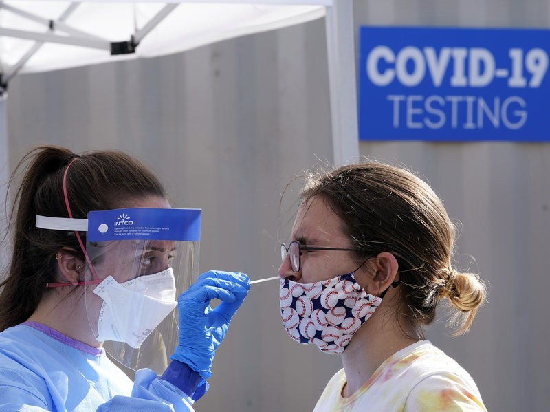 A woman is tested for the coronavirus at a walk-up testing site Friday in Seattle. Testing availability and reliability continue to be problems in the U.S. fight against the virus. Elaine Thompson/AP
