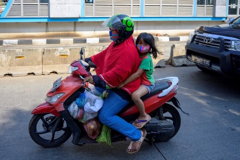 A woman and her daughter wear face masks as a prevention measure against the COVID-19 while and riding a motorbike in Jakarta, September 17, 2020. (PHOTO / AFP)